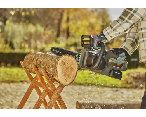 Tronçonneuse à batterie coupant une bûche sur un chevalet en bois