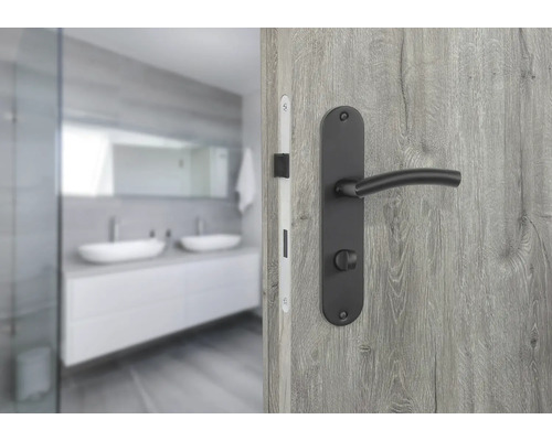 Tür mit schwarzer Türgarnitur und Blick in ein Badezimmer mit Waschbecken