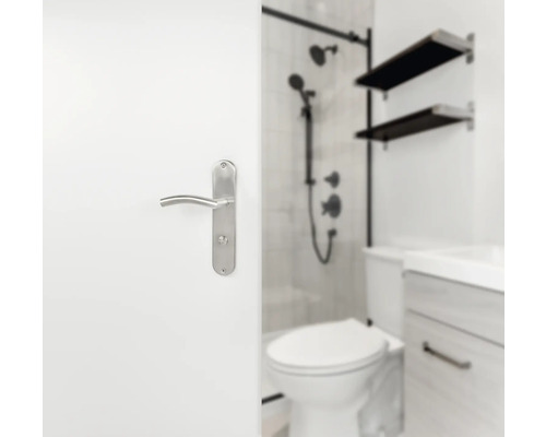 Vue partielle d''une salle de bains avec toilettes, lavabo, douche et poignée de porte sur une porte blanche