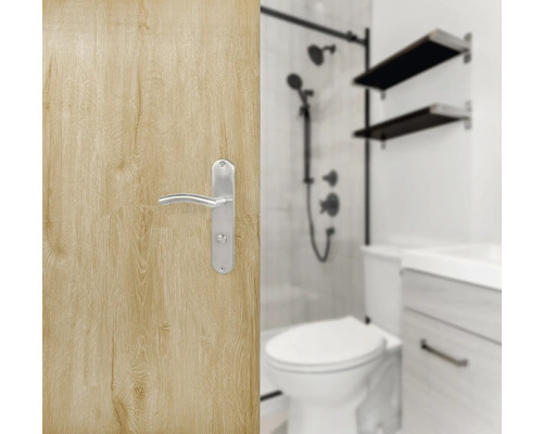 Porte en bois clair avec poignée de porte argentée et salle de bain en arrière-plan