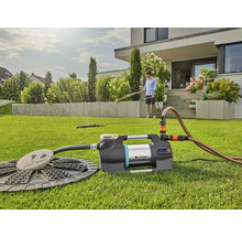 Scène d''irrigation de jardin avec pompe domestique, arroseur de pelouse et famille en arrière-plan