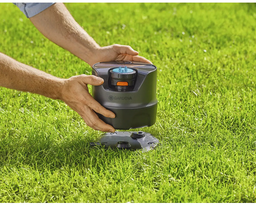 Gardena Viereckregner im Rasen, der von Händen gehalten wird