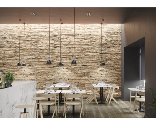 Intérieur avec revêtement mural aspect pierre, suspensions et tables avec chaises.