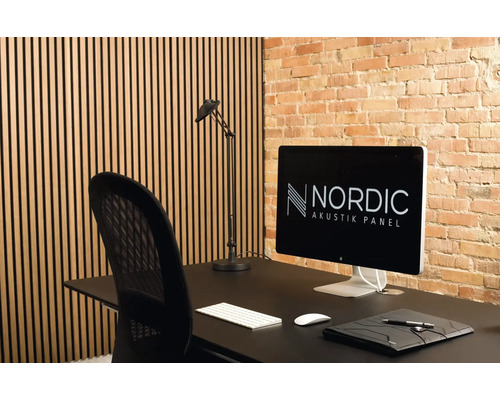 Einrichtung mit Akustikpaneelen, Schreibtisch, Lampe und Bürostuhl vor einer Backsteinwand
