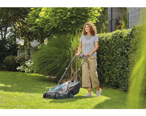 Frau bedient Rasenmäher im Garten