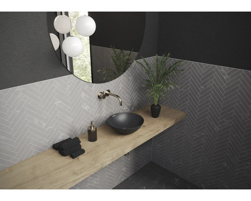 Salle de bain avec lavabo, miroir, robinet, étagère et carrelage à chevrons.