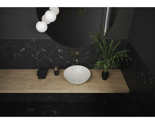 Salle de bains moderne avec lavabo à poser, plan de travail en bois et carreaux à chevrons foncés.