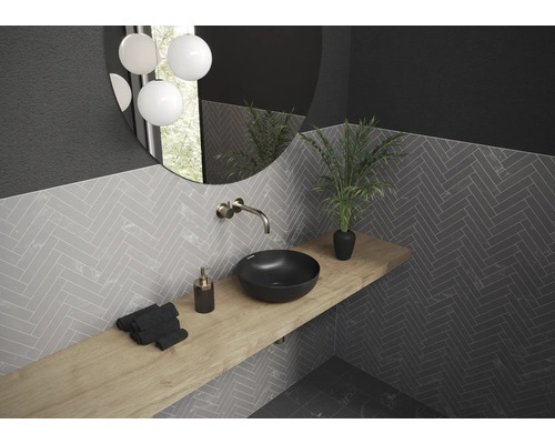 Salle de bains avec lavabo, robinet, miroir, plante et carrelage à chevrons