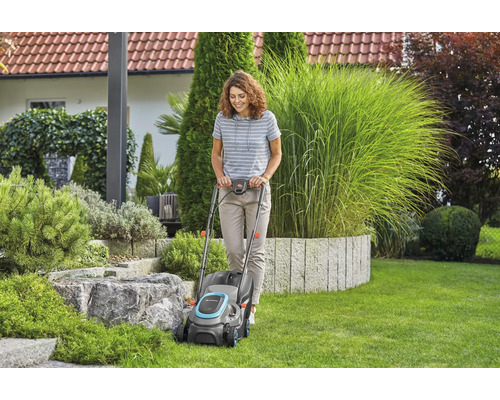 Frau benutzt Rasenmäher im Garten.