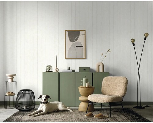 Wohnzimmer mit grüner Kommode, Dekorationen, Sessel und Hund auf einem Teppich