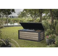 Geöffnete Gartenbox aus Holz und Kunststoff zur Aufbewahrung von Kissen und Gartenutensilien im Garten.