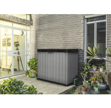 Armoire de jardin en plastique sur une terrasse devant un mur en briques.