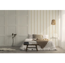 Schlafzimmer mit gestreifter Tapete, Bett und Holzhocker