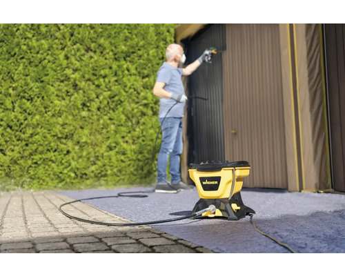 Homme peignant une porte de garage avec un système de pulvérisation de peinture Wagner