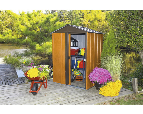 Abri de jardin avec porte ouverte et outils de jardin sur terrasse en bois