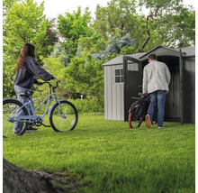 Scène de jardin avec abri de jardin et deux personnes avec des vélos sur une pelouse