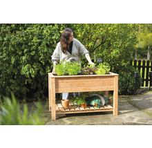 Jardinière sur pieds en bois avec des plantes et une femme dans le jardin