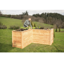 Jardinière en bois dans le jardin avec une femme qui jardine