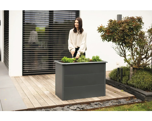 Jardinière surélevée en métal avec une femme plantant dans le jardin