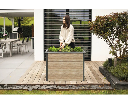 Une femme travaille dans le jardin avec un bac à fleurs sur une terrasse