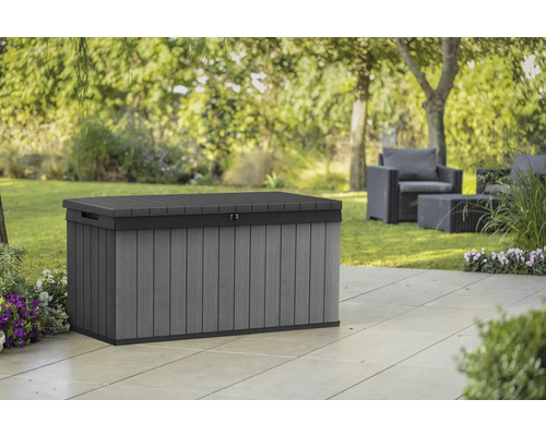 Coffre de jardin gris en plastique sur une terrasse avec des meubles de jardin à l''arrière-plan