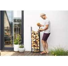 Homme remplissant un range-bûches avec des bûches dans le jardin