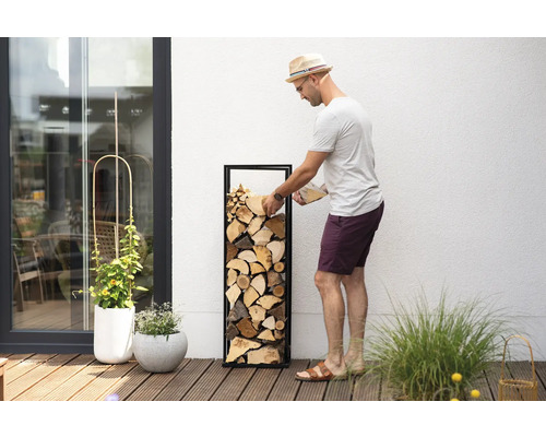 Un homme remplit un casier à bois de chauffage sur une terrasse