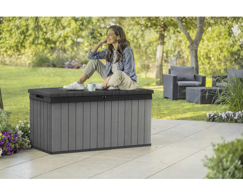 Scène de jardin avec coffre de rangement en plastique gris avec une femme assise dessus