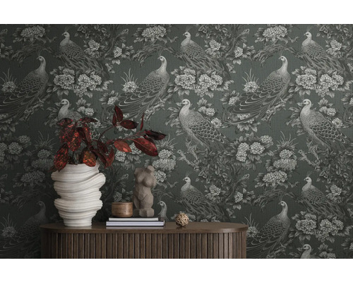 Detailaufnahme einer Wand mit einer Tapete mit Pfauen und Blumenmuster, mit einem Tisch und Dekorationen davor
