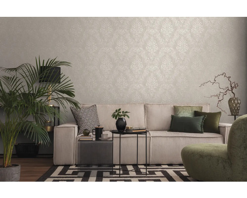 Wohnzimmer mit gemusterter Tapete, Sofa, Zimmerpflanze und dekorativen Elementen für ein gemütliches Ambiente