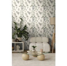 Wohnzimmer mit floral gemusterter Tapete, Sessel, Tisch und Zimmerpflanzen.