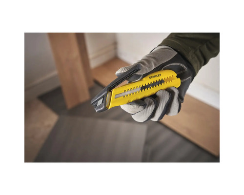 Eine Hand in einem Handschuh hält ein Stanley Teppichmesser.