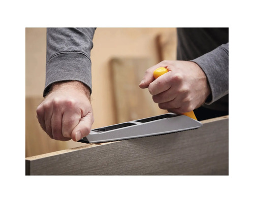 Une personne utilise une râpe à rabot pour travailler une pièce de bois.