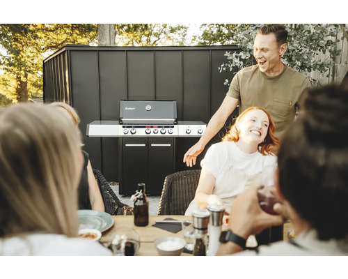 Personen sitzen an einem Tisch mit einem Enders Gasgrill im Hintergrund.