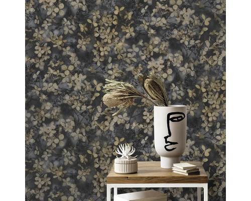Nahaufnahme einer Wand mit floralem Tapetenmuster, das auf einem kleinen Tisch mit Dekoration arrangiert ist.