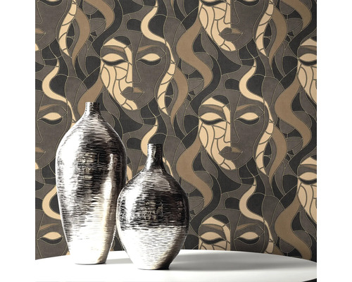Zwei silberfarbene Vasen auf einem Tisch vor einer gemusterten Tapete mit Gesichtern.