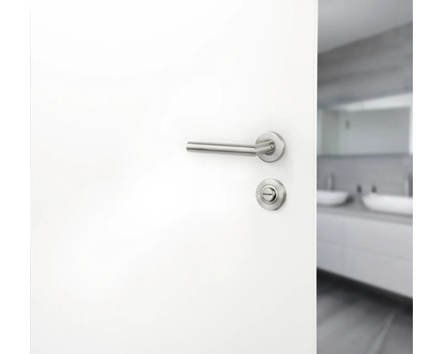 Weiße Tür mit Türgriff und Schloss vor einem Badezimmer