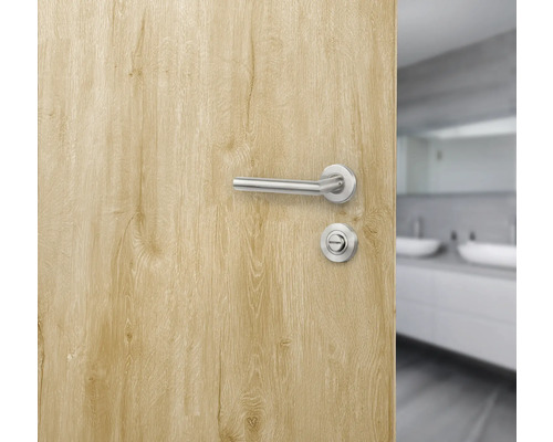 Geöffnete Tür mit Türgriffgarnitur und Badezimmer im Hintergrund