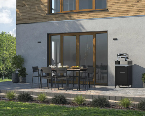 Extérieur avec table à manger, chaises et four à pizza devant un mur de maison