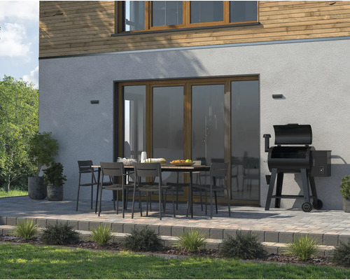 Aussenbereich mit Esstisch, Stühlen und Grill neben dem Haus