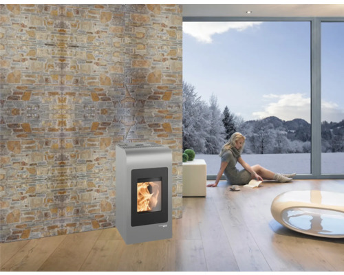 Salon avec poêle à pellets, mur en pierre naturelle et fenêtre avec paysage hivernal