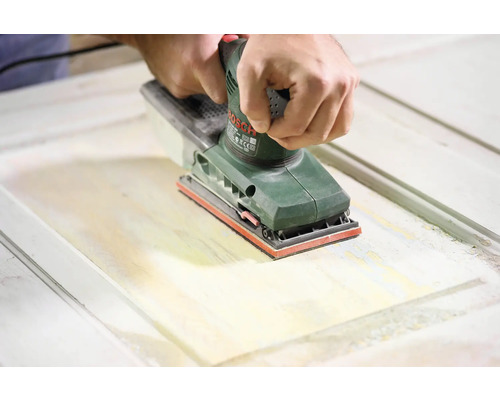 Eine Person verwendet einen Schwingschleifer von Bosch zum Abschleifen einer Holztür.