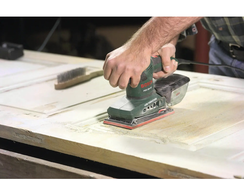 Mann schleift Holztür mit einem Schwingschleifer von Bosch