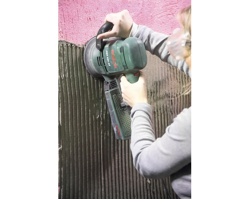 Une personne utilise une ponceuse excentrique Bosch pour poncer un mur.