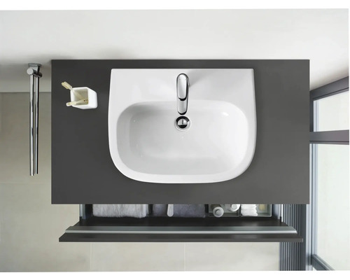 Aufsicht auf ein Waschbecken mit Unterschrank, Handtuchhalter, Zahnputzbecher und Pflegeprodukten