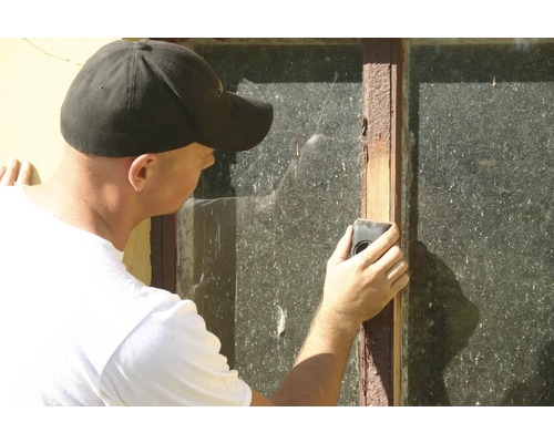 Eine Person reinigt ein Fenster mit einem Reinigungswerkzeug.
