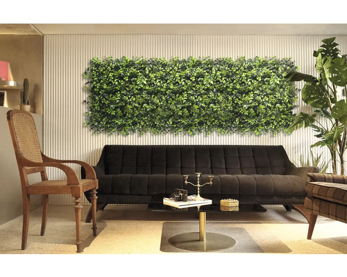 Dekoratives Interieur mit Pflanzenwandpaneel über einem schwarzen Sofa.