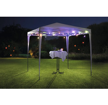 Tente de réception avec guirlande lumineuse et table de bistro sur une pelouse