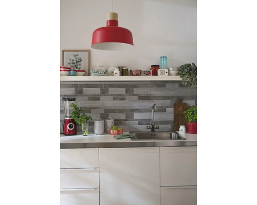 Cuisine claire avec évier, robinet, appareils de cuisine et suspension rouge.