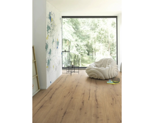 Espace de vie lumineux avec sol stratifié imitation bois, fauteuil et fenêtre
